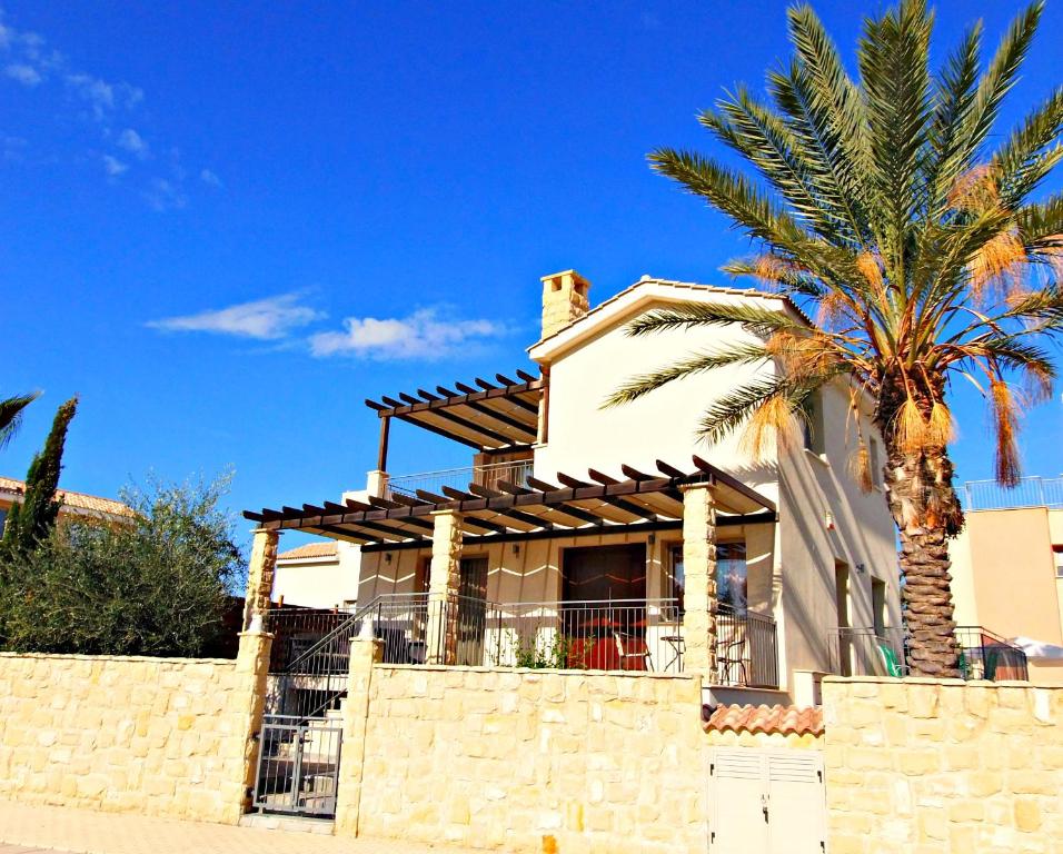 a house with a palm tree in front of a wall at Villa Lalianda Sandy Beach Villas - Private Pool - Jacuzzi - Private Beach Area in Polis Chrysochous