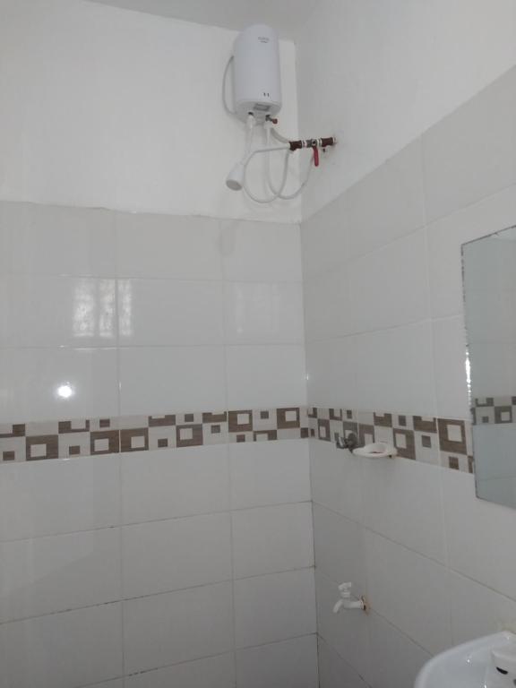 a white bathroom with a shower and a sink at Cossy Homes in Mtwapa