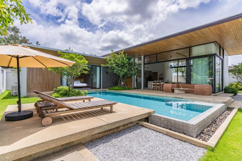 a house with a swimming pool and an umbrella at Botanica Zen by Villacarte in Ban Phru Champa