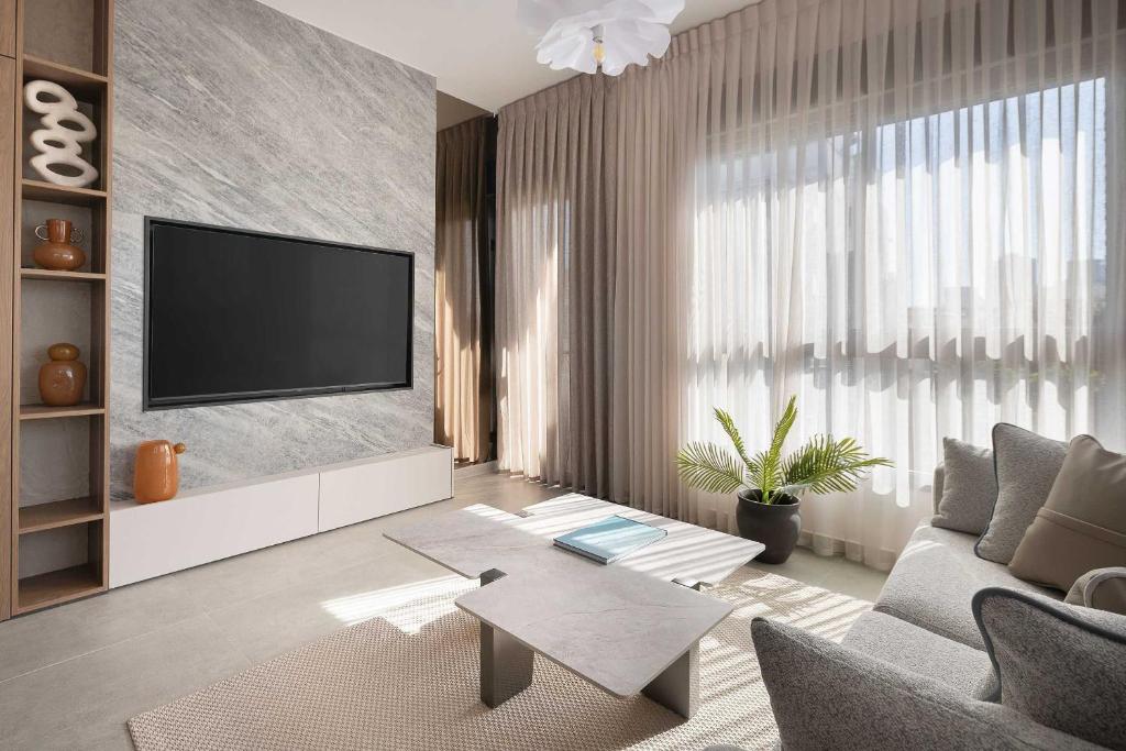 a living room with a television on a wall at 2BR Balcony High Floor - Dizengoff Square View - MAMAD D80 in Tel Aviv