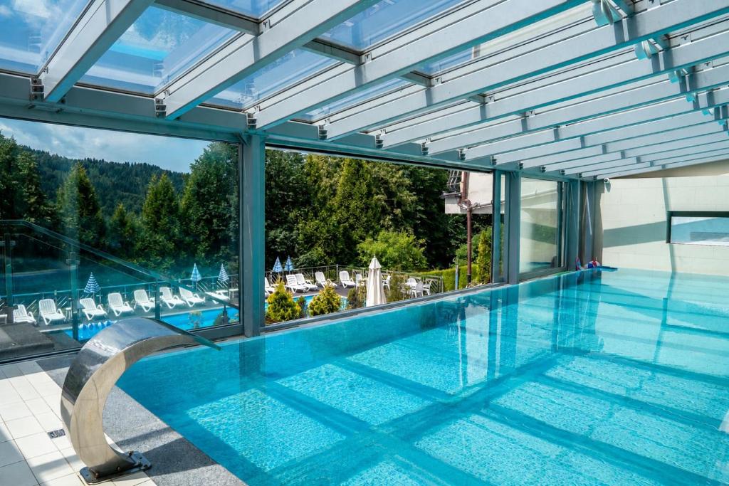 a swimming pool with a view of a house at Hotel New Wave Wisła in Wisła