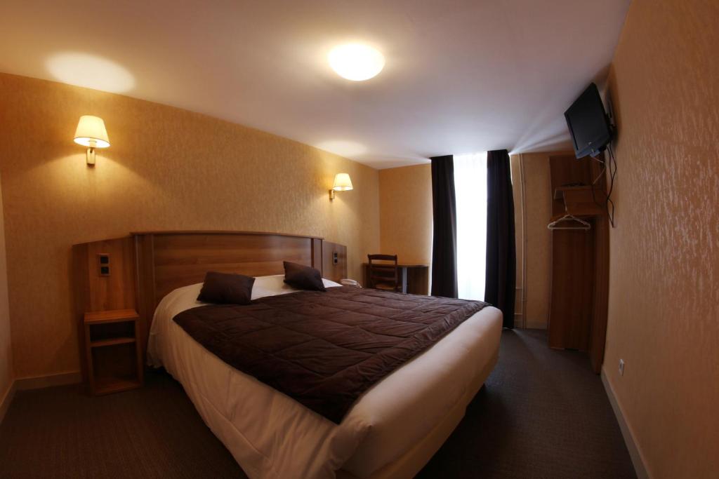 a bedroom with a large bed in a hotel room at Hotel De L'Abbaye in Sauxillanges