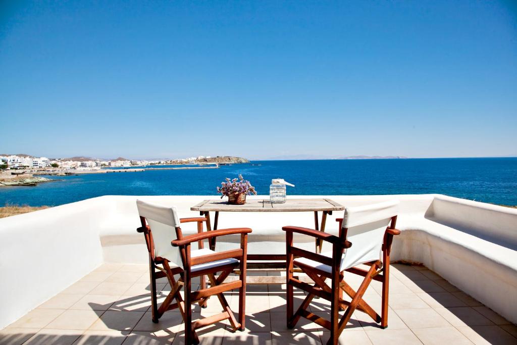 - stół i krzesła na balkonie z widokiem na ocean w obiekcie Orionides w mieście Tinos