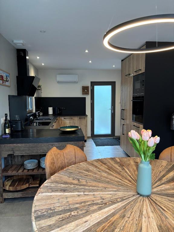 a kitchen and dining room with a table with a vase of flowers at Le Petit Nid Gerardmer in Gérardmer