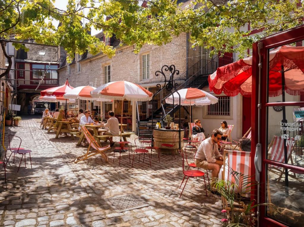 a group of people sitting at tables with umbrellas at Mustard Hostel in Dijon