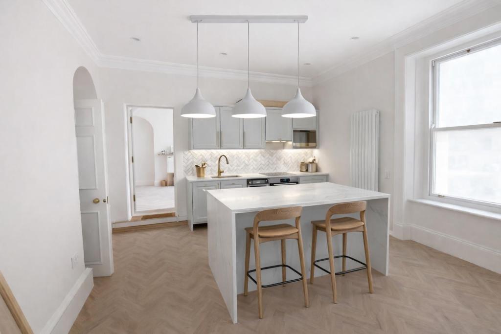 a white kitchen with a island and two stools at The Bridge York in York