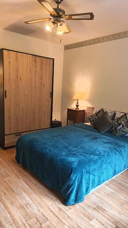 a bedroom with a blue bed with a ceiling fan at Studio privatif DATCHA in Saint-Germain-en-Laye