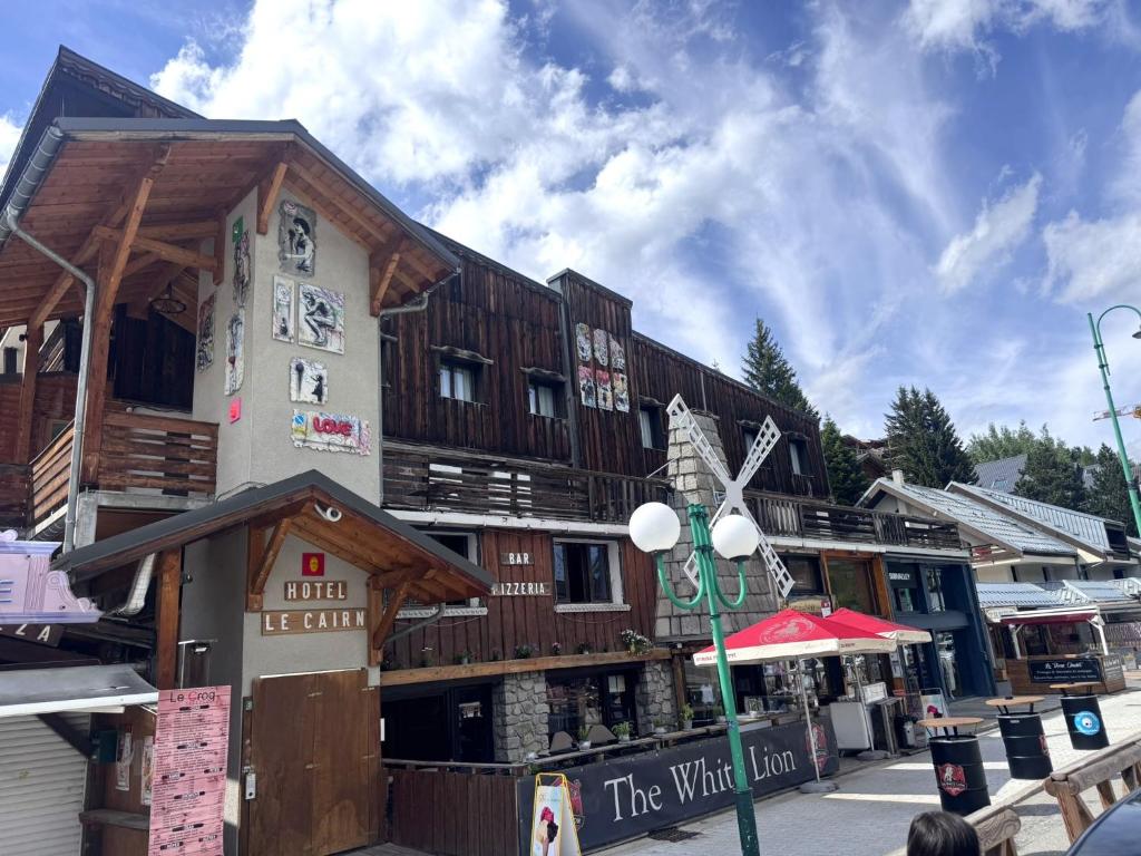 a wooden building with a store on a street at Logis Hôtel Le Cairn in Les Deux Alpes