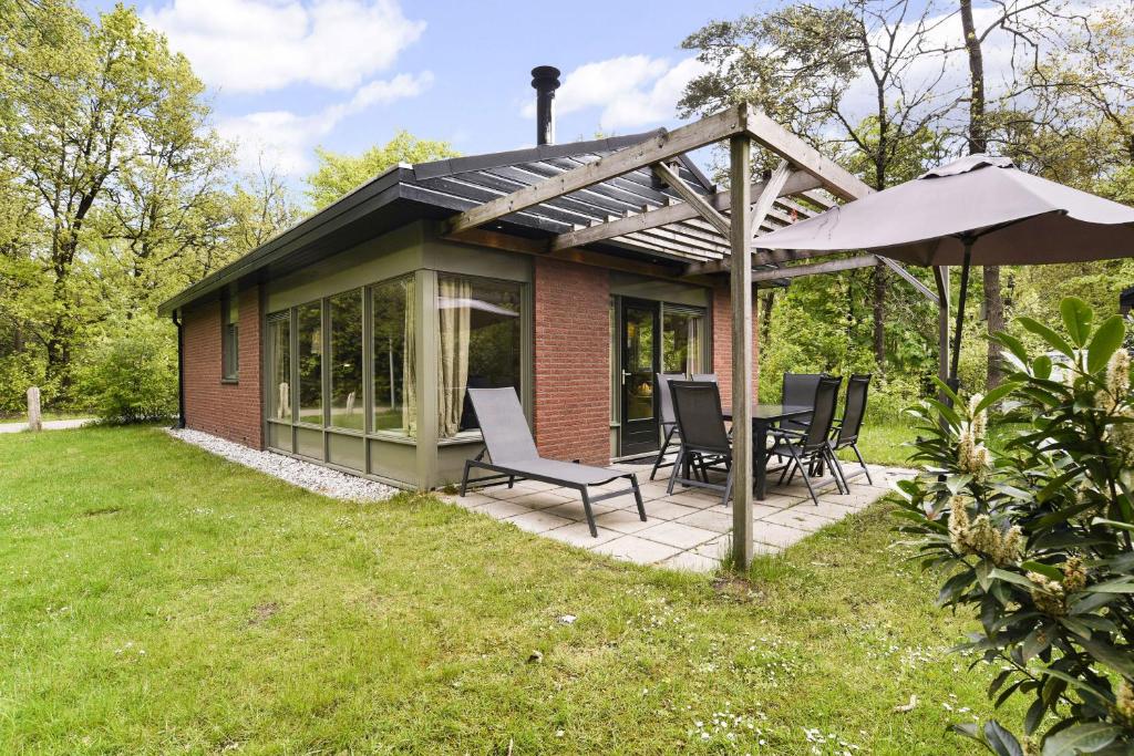 a patio with a table and chairs and an umbrella at Summio Parc Heihaas in Putten