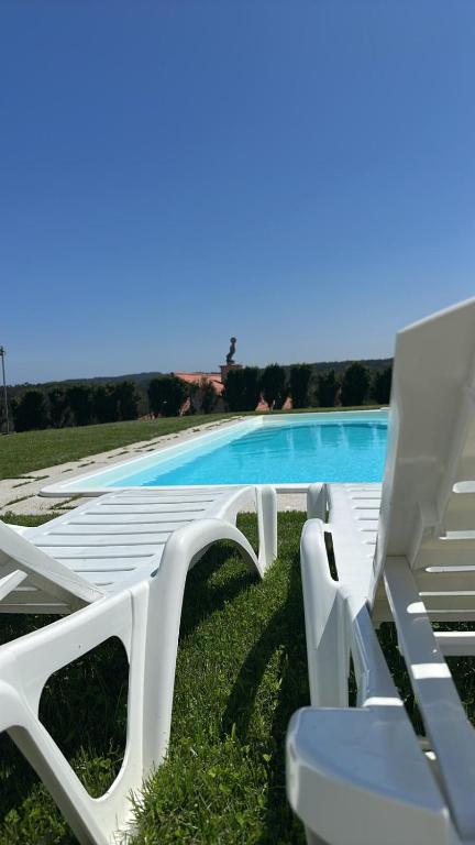 a group of white lounge chairs next to a swimming pool at Villa Cariño - Apartamento en Malpica de Bergantiños in Malpica