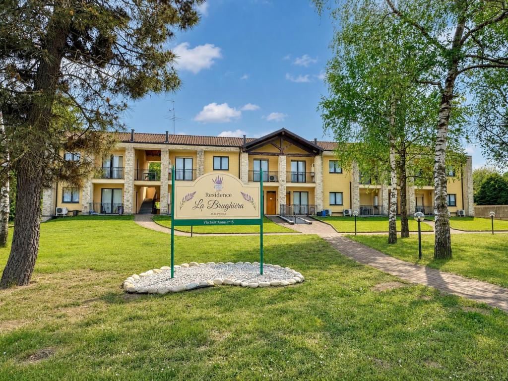 a building with a sign in the middle of a park at Residence La Brughiera Malpensa in Lonate Pozzolo