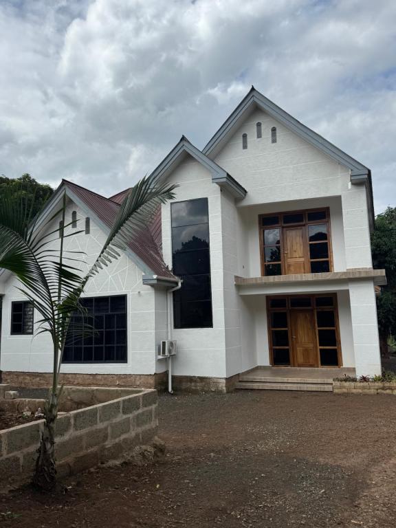 a white house with a palm tree in front of it at Kili Maisha Grand Home in Moshi