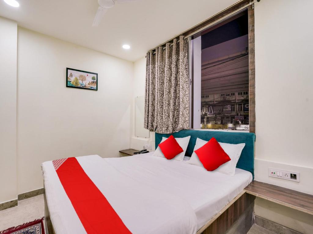 a bedroom with a bed with red pillows and a window at HOTEL O M J HEIGHTS in Garhā