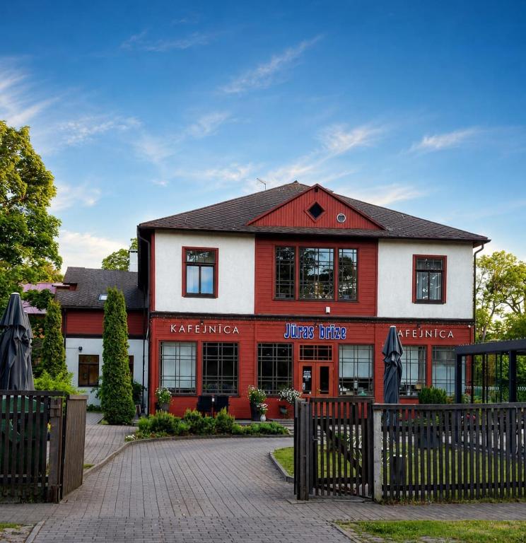 a red and white building with a fence in front of it at Jūras Brīze in Ventspils