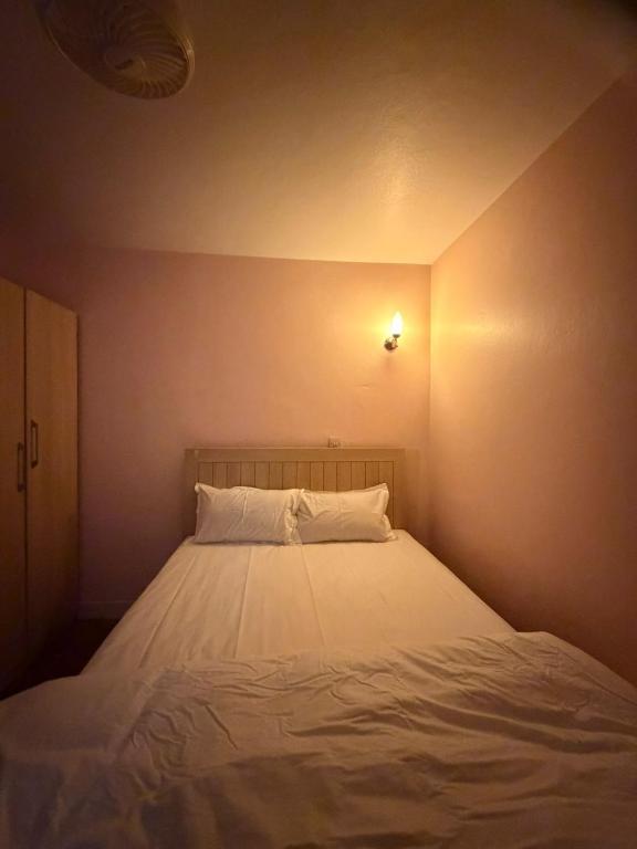 a bedroom with a white bed with a light on the wall at 1bhk apartment in Kathmandu