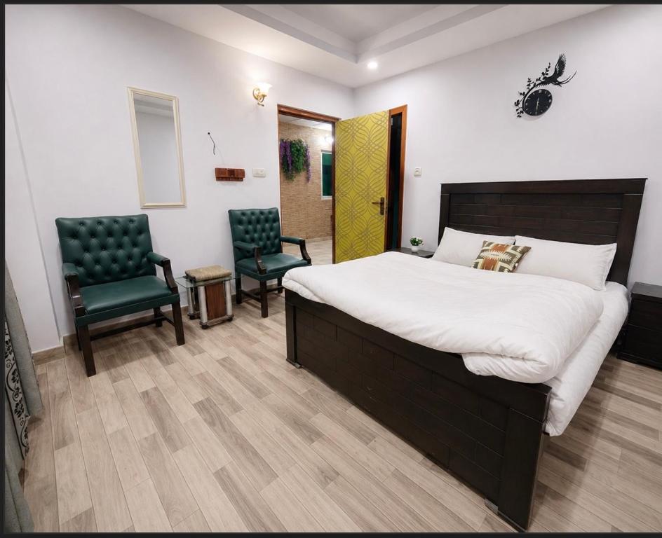 a bedroom with a large bed and two chairs at AGH Guesthouse & Rooms in Islamabad