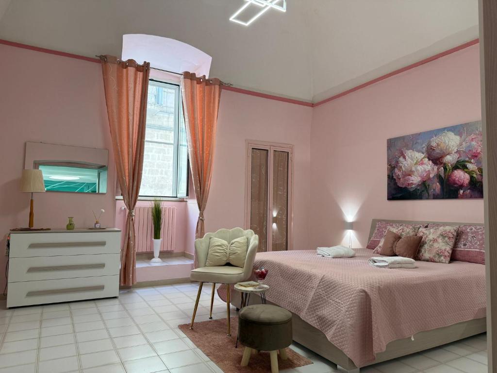 a pink bedroom with a bed and a chair at Domus Lucrezia in Bisceglie