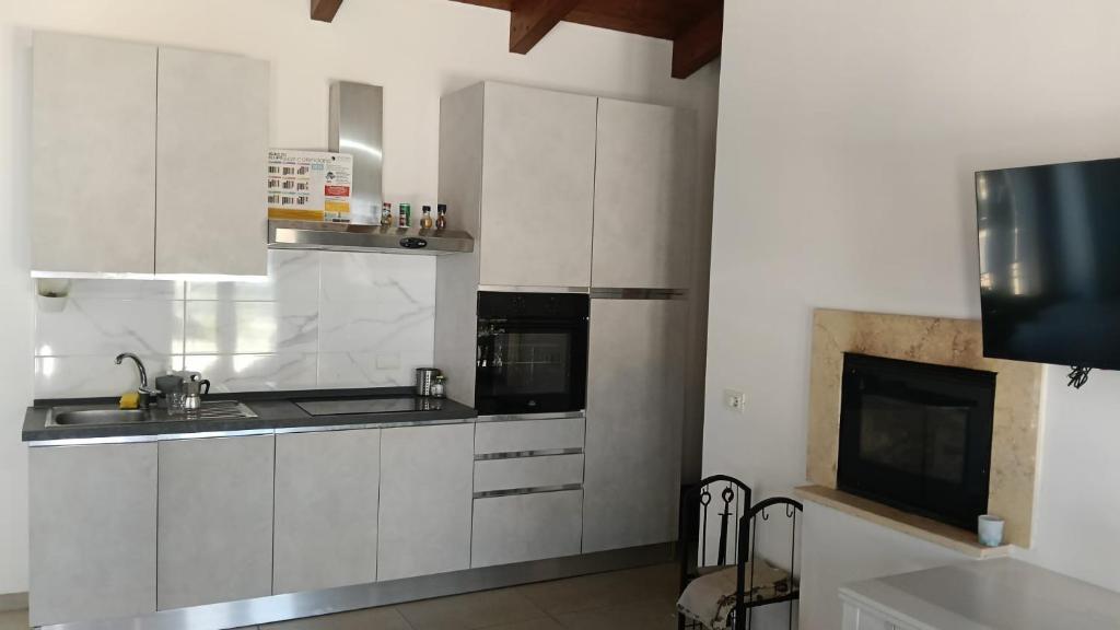 a kitchen with white cabinets and a sink and a tv at Oasi 29 in Morlupo