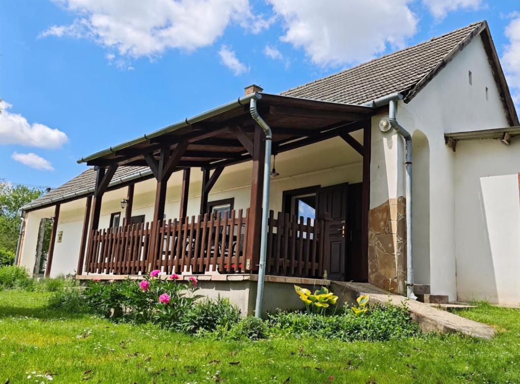 a cottage with a porch with flowers in the yard at Minor Major Vendégház in Somogyacsa