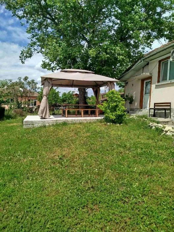 a gazebo in a yard next to a house at Стаи за гости VIVIA in Veliko Tŭrnovo
