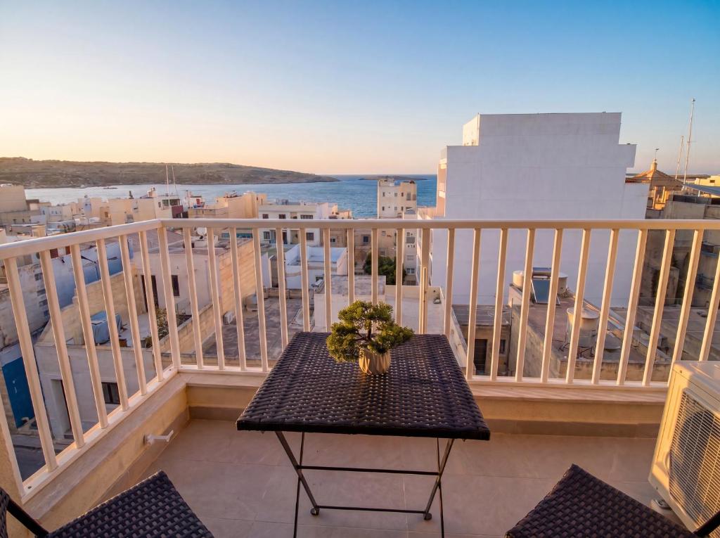 a table on a balcony with a view of the ocean at Merhba Court Apartments - St Pauls Bay in St. Paul's Bay