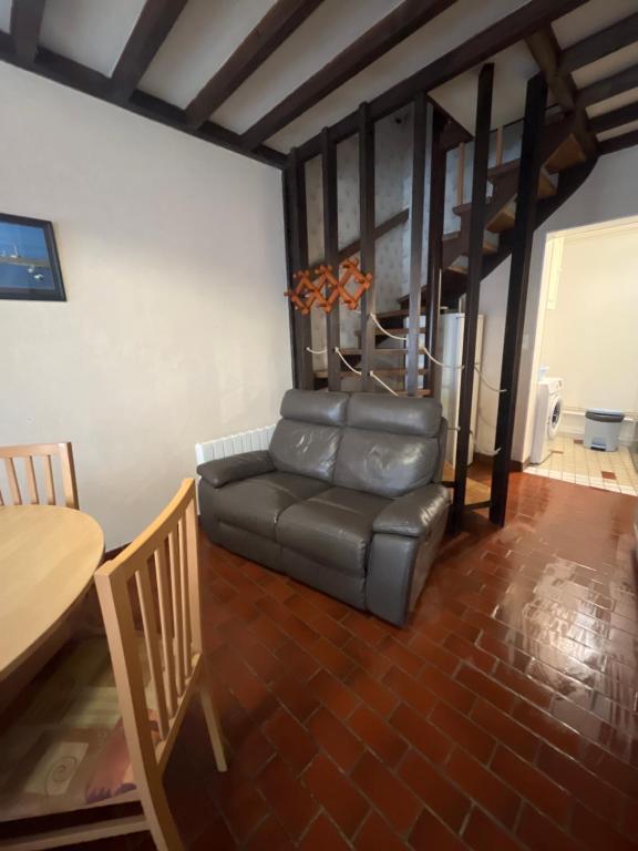 a living room with a leather couch and a table at "Les Mouettes" Maison de pêcheur en centre ville in Saint-Vaast-la-Hougue