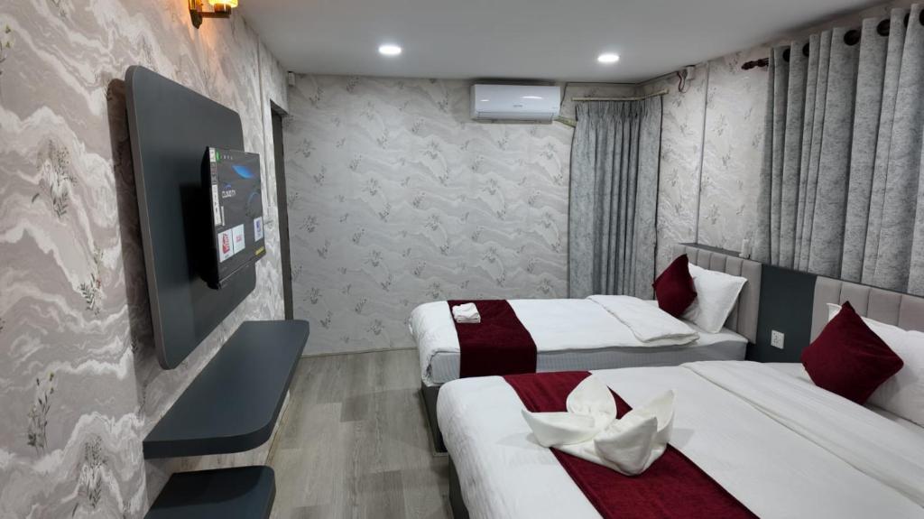 a hotel room with two beds and a flat screen tv at Bhandari hotel and sekuwa corner in Pashupatināth