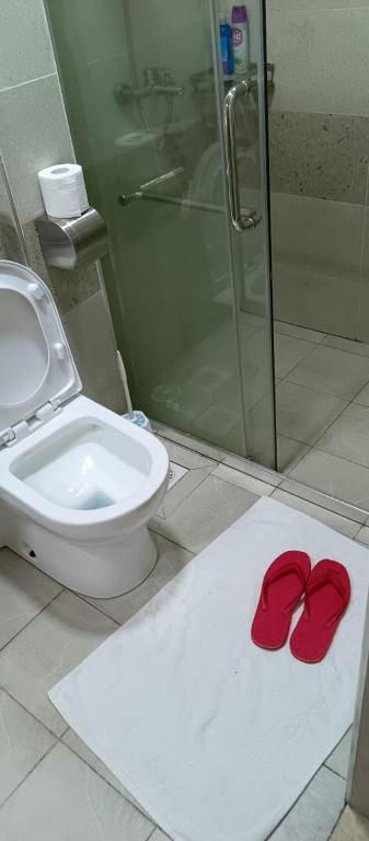 a bathroom with a toilet and a pair of red slippers at Kaisa Studio apartments in Nairobi