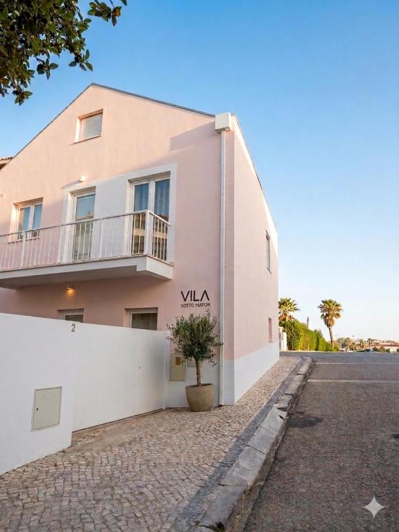a pink building with a potted plant in front of it at Vila Sotto Mayor in Figueira da Foz
