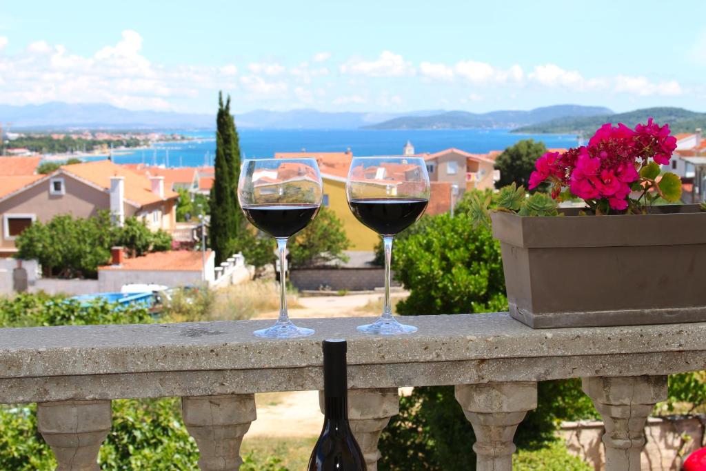 two glasses of red wine sitting on a ledge at Apartments & Rooms Milena in Vodice