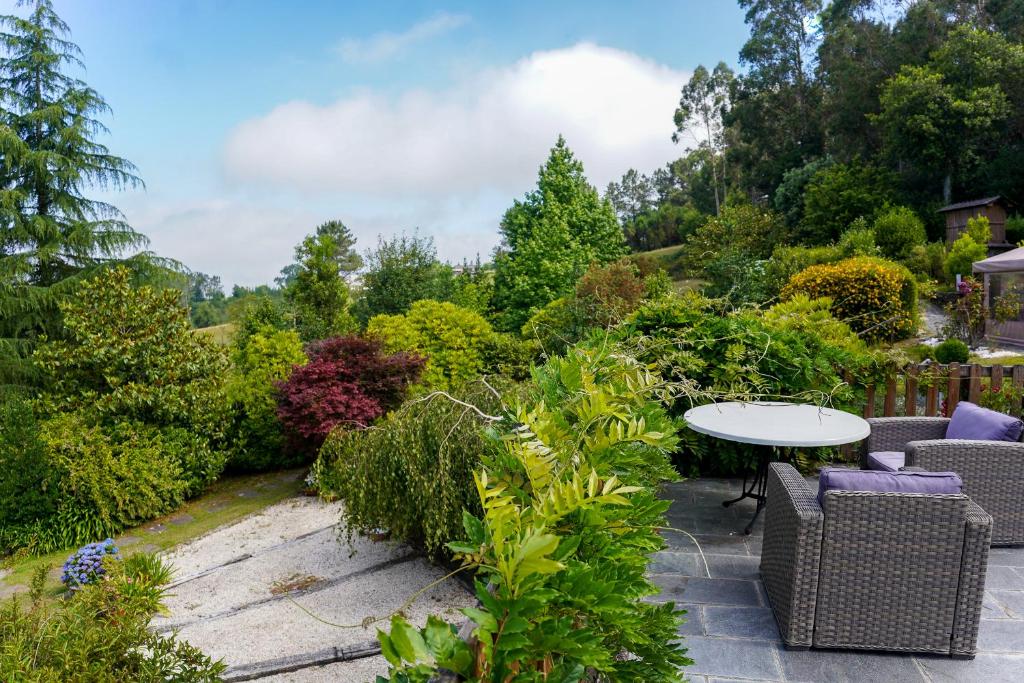 a patio with a table and chairs in a garden at Casa Piñeiro in Monfero