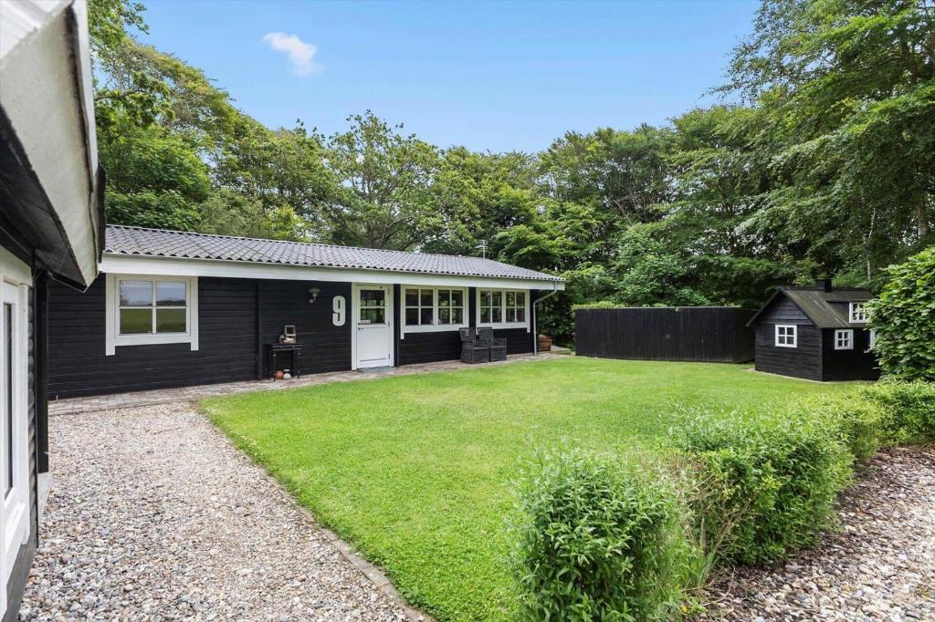 a black house with a yard in front of it at LF10999-Thyholm-Ringvejen-9 in Thyholm