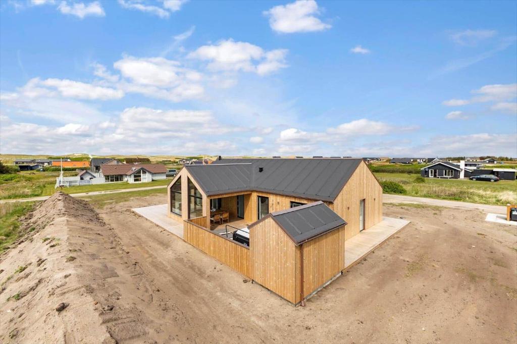 a house with a black roof on a dirt lot at 391-Harboore-Slettevej-33 in Harboør