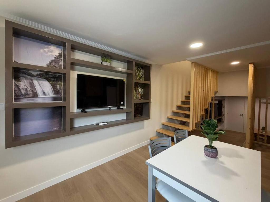 a living room with a tv on the wall and a table at casa Angelita in Mourillones