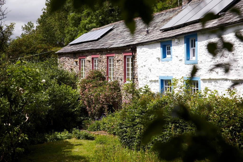 stary kamienny dom z czerwonymi i niebieskimi oknami w obiekcie Lowthwaite B&B w mieście Watermillock