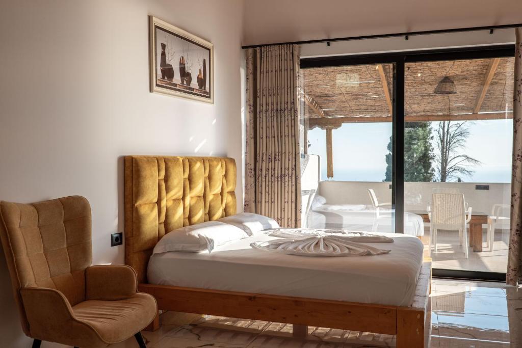 a bedroom with a bed and a chair and a balcony at Hotel Panorama Piqeras in Piqeras