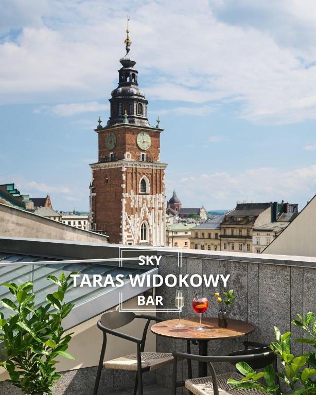 a table and chairs on a balcony with a clock tower at Hotel Experior Boutique - Destigo Hotels in Krakow