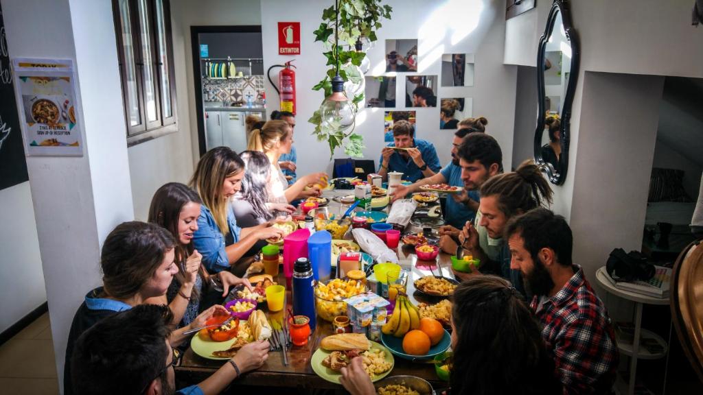 Eine Gruppe von Menschen, die an einem Tisch sitzen und Essen essen. in der Unterkunft The Lights Hostel in Málaga