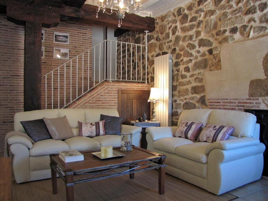 a living room with two couches and a stone wall at Casa del Tío Benito 2H in Molinos de Duero