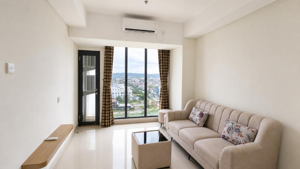a living room with a couch and a large window at SleepRest @ Pollux Habibie in Batam Center