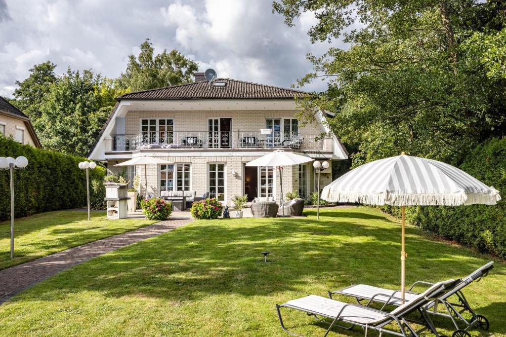 a house with two lawn chairs and an umbrella at Exklusive Traumvilla mit Sauna in Hamburg