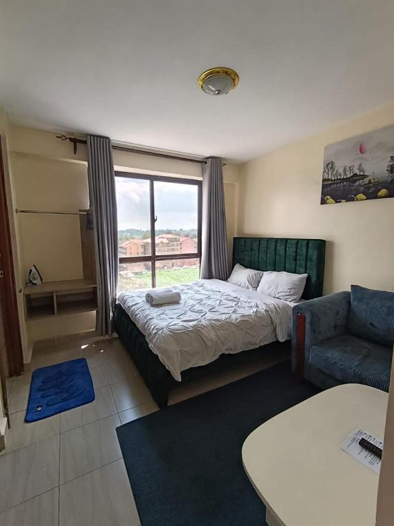 a bedroom with a bed and a couch and a window at Majestic studio in Rungiri