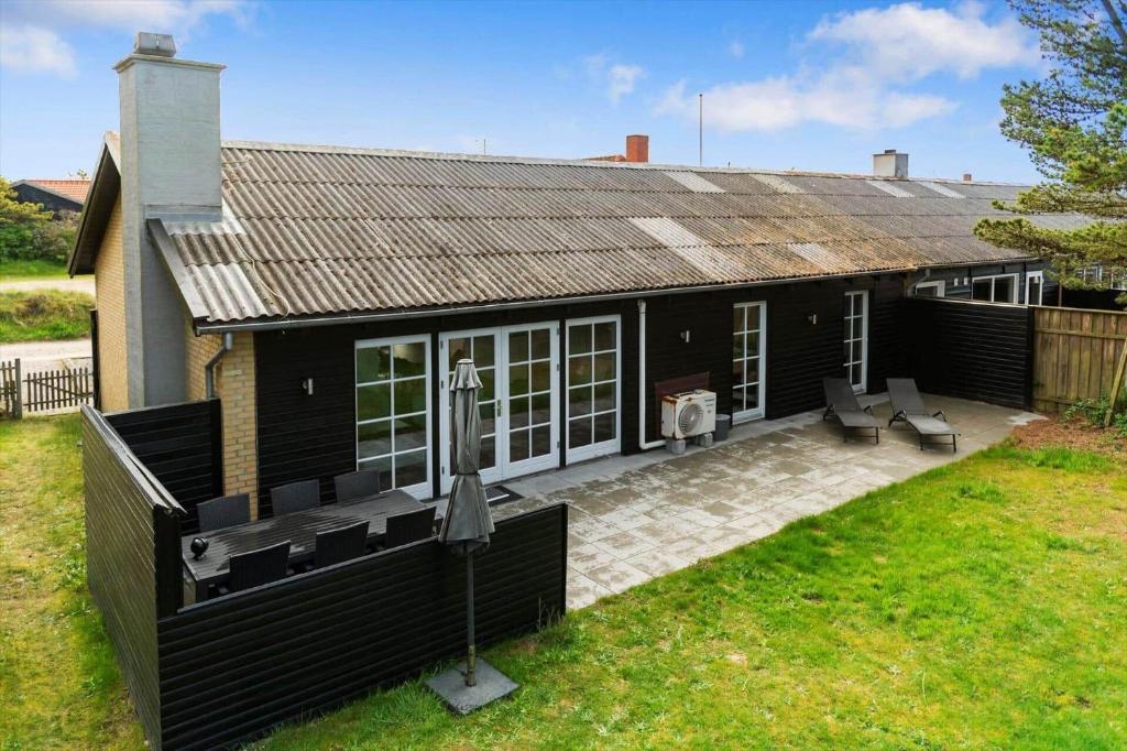 a black house with two chairs and a patio at BV225-Blavand-Blavandvej-5-E in Blåvand