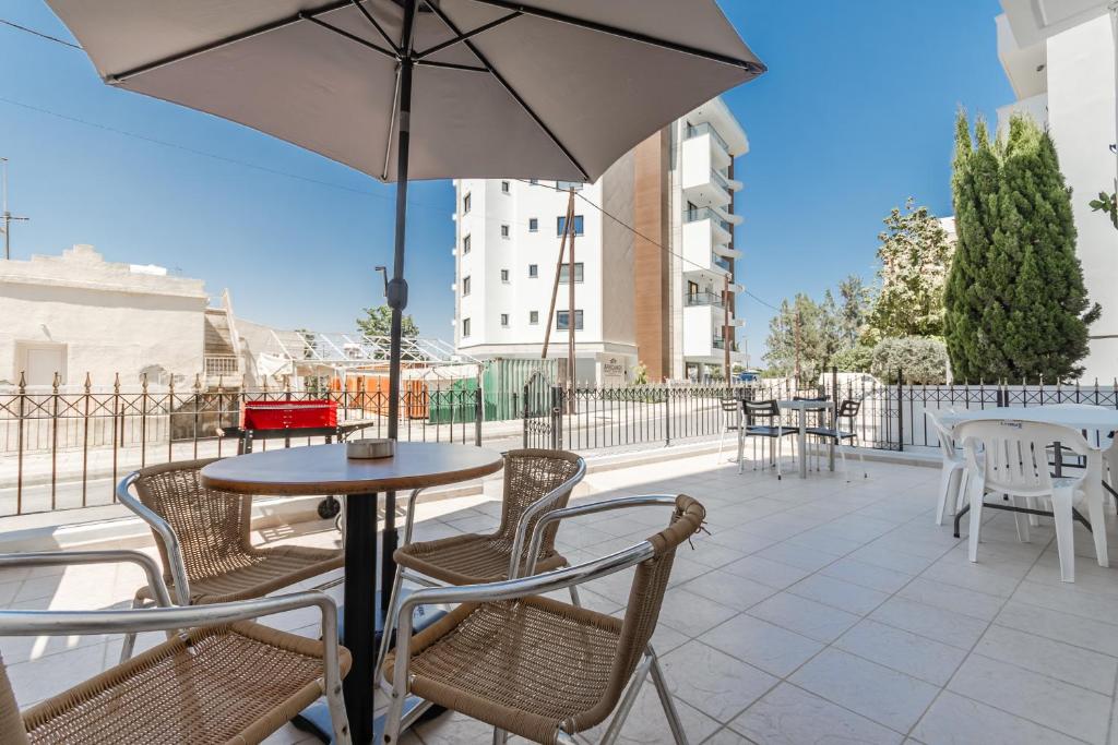 a table and chairs with an umbrella on a patio at Andreas Beachfront Hostel in Larnaca