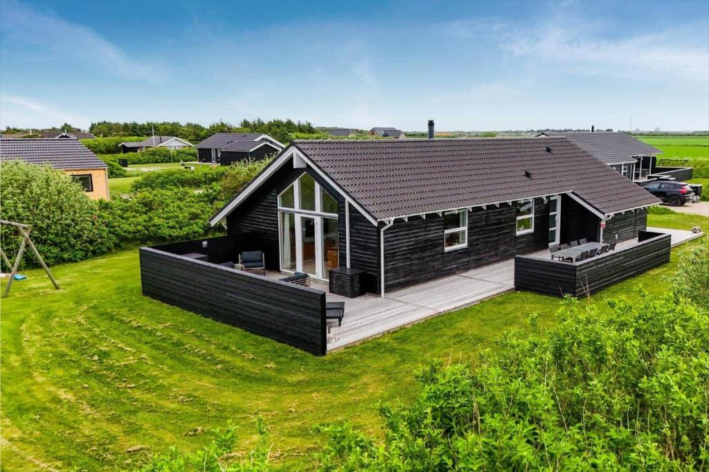 a house with a black roof on a green lawn at 393-Harboore-Fourmivej-10 in Harboør