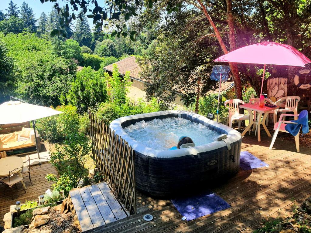 a hot tub in a yard with a table and an umbrella at La cazelle, dependance du 18 siecle, jacuzzi in Carsac-Aillac