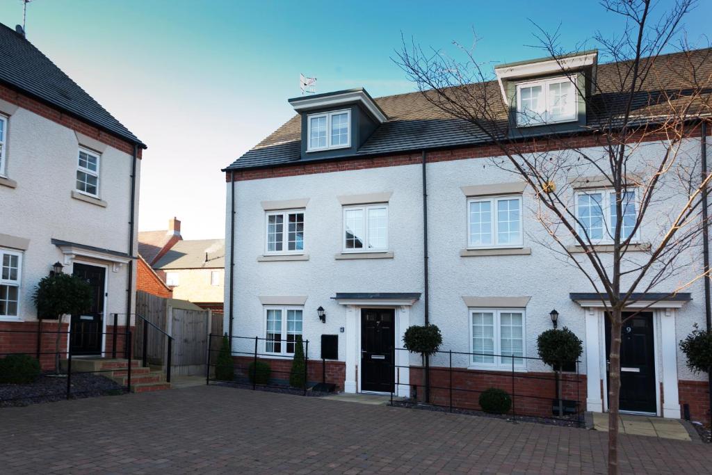 a white house with a black roof at DBS Serviced Apartments - The Townhouse in Castle Donington