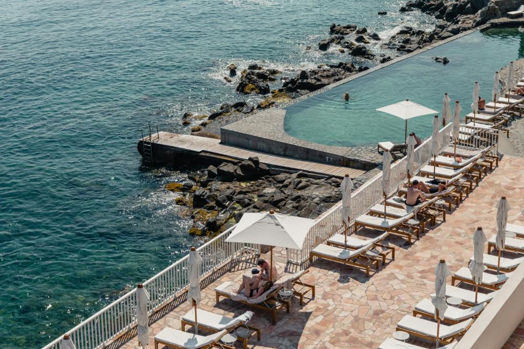 a group of chairs and umbrellas next to a pool at Les Roches Rouges, a Beaumier hotel in Saint-Raphaël