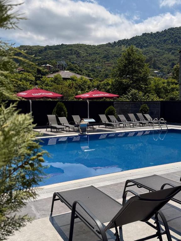 a swimming pool with lounge chairs and umbrellas at Апарт-отель Homeland in Gonio