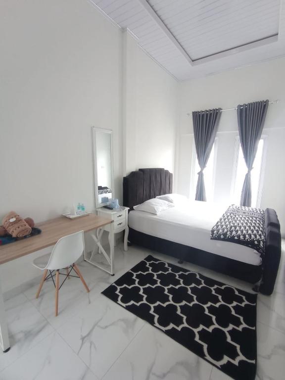 a bedroom with a bed and a desk and a rug at Detara Homestay Syariah in Takengon